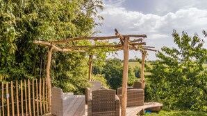 A pool area with wicker furniture and a wooden pergola.