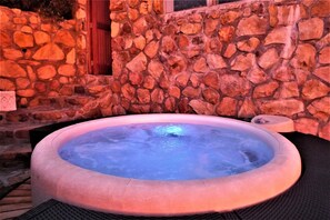 A hot tub surrounded by stone walls and a wooden door.