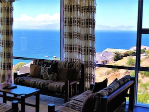 Relax in this inviting living room with a sofa set, coffee table, and scenic ocean and mountain views.