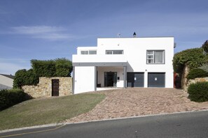 A modern two-story house with a stone facade, a paved driveway, and a garage.