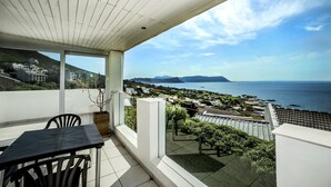 A balcony with a view of the sea and distant mountains.