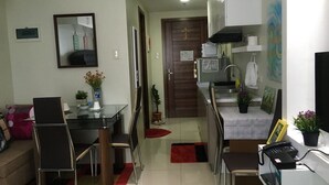 Un espace de vie compact comprenant un coin repas, une kitchenette et un petit couloir.