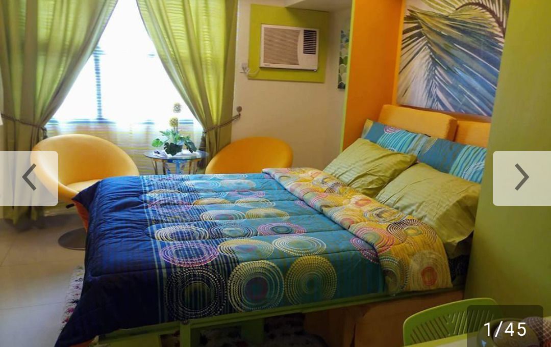 A bedroom with a bed, two chairs, a small table, and a window with curtains.