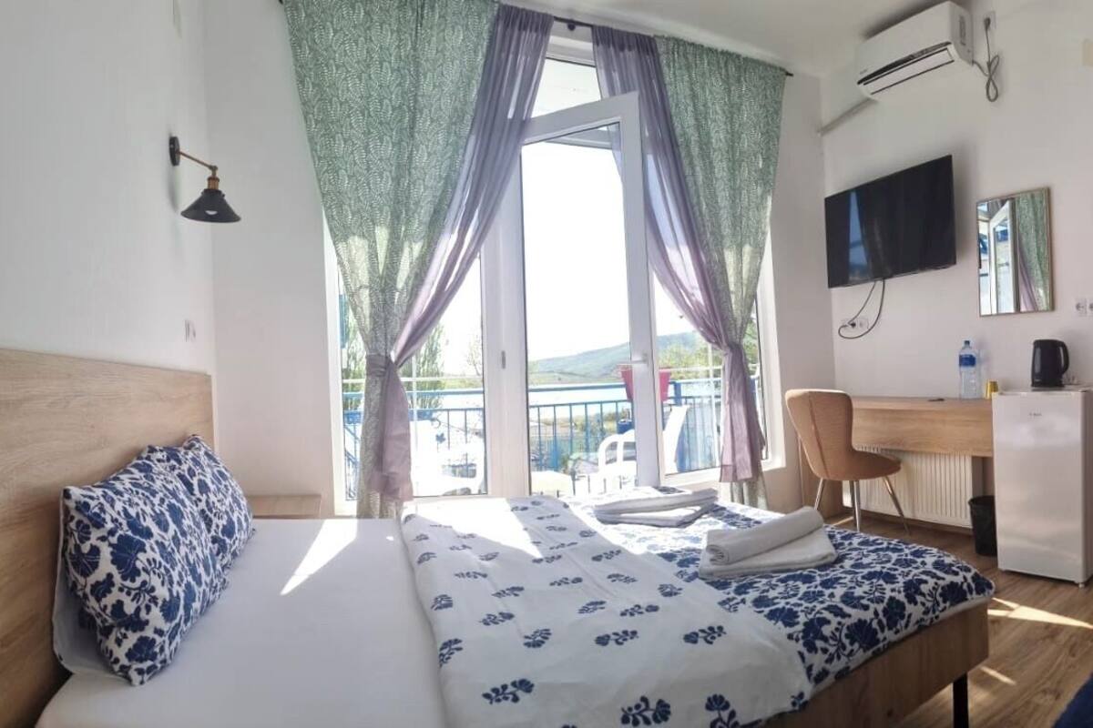 Habitación de hotel con cama, escritorio, silla, televisor y armario.
