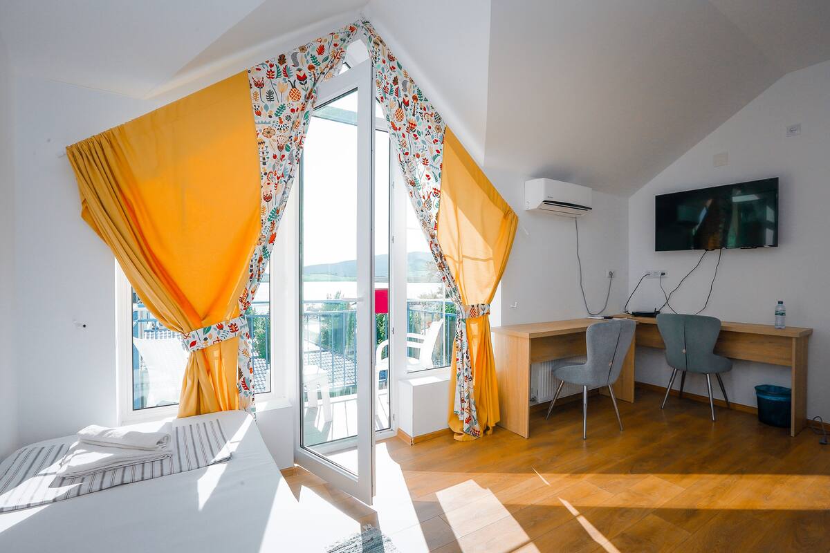 Una habitación moderna con cama, escritorio, dos sillas y televisor.