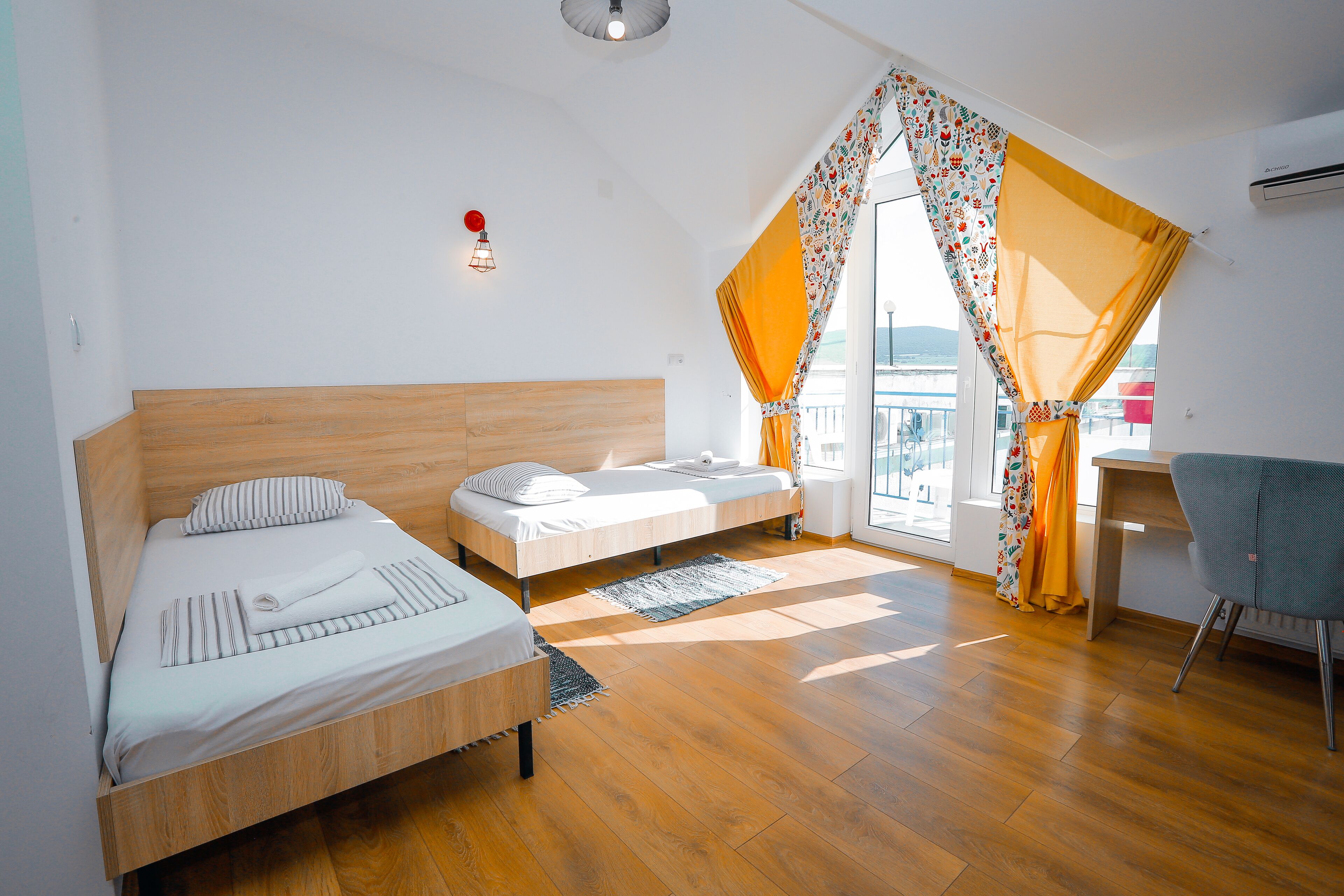 A bedroom with two beds, a desk, and a chair.