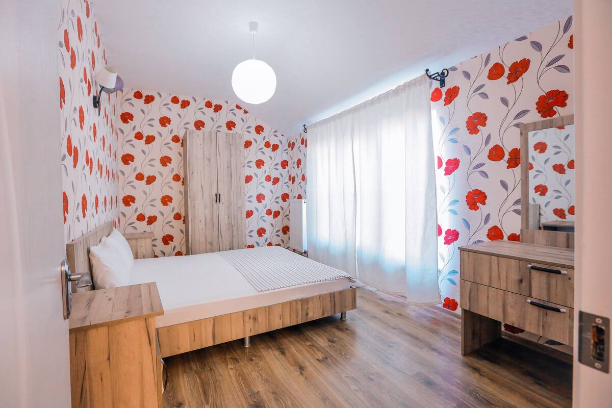 Un dormitorio con una cama y cómoda de madera, y un espejo.