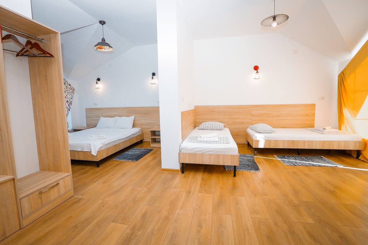 Un dormitorio moderno con dos camas, suelo de madera e iluminación colgante.