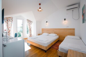 Una habitación de hotel moderna con una cama de madera, un escritorio pequeño y una ventana con cortinas florales.