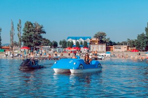 Un cuerpo de agua con barcos y una zona de playa con sombrillas y gente.