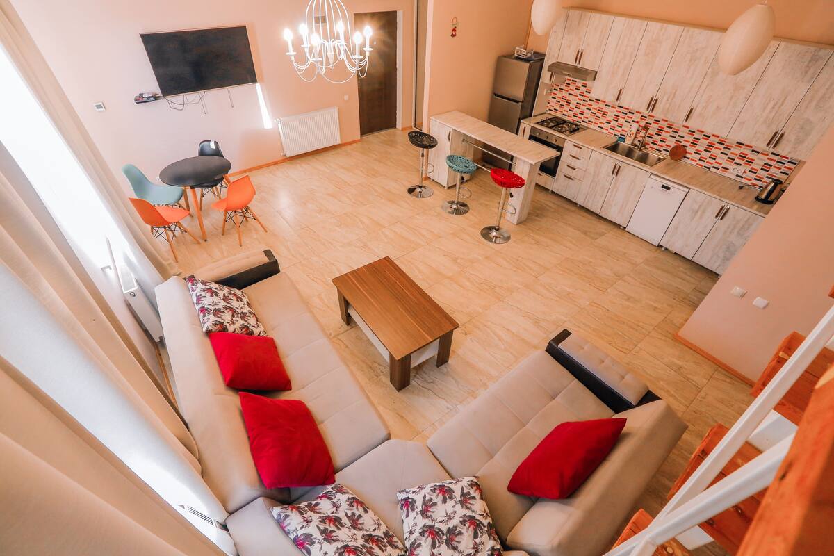 Una sala de estar moderna con un conjunto de sofás, una mesa de centro y una cocina con una mesa de comedor y sillas.