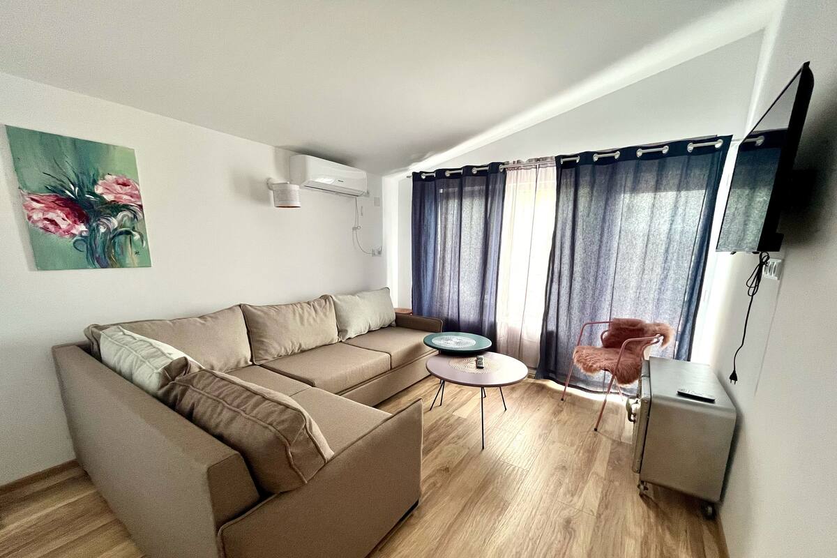 Una sala de estar moderna con un sofá, una mesita redonda, un sillón y un televisor.