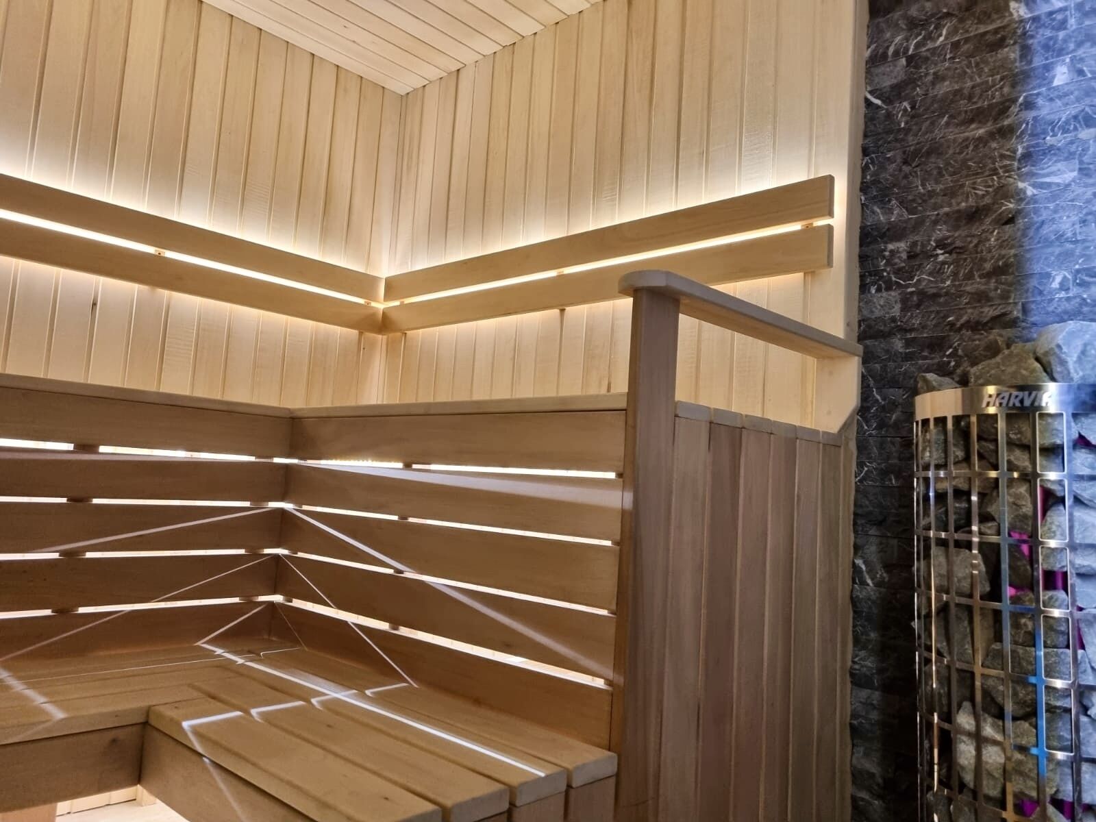 A wooden sauna with slatted benches and a stone wall.