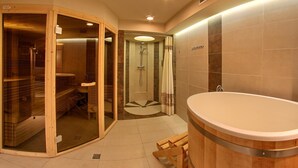 Une salle de bain moderne dotée d’une grande baignoire, d’une douche à parois de verre et d’un sauna en bois.