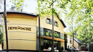 A two-story building with a yellow facade and a sign reading "HOTEL ZACISZE".