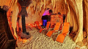 Une pièce souterraine aux murs en bois, avec une structure centrale en forme d’arbre et des chaises orange disposées en rangées.
