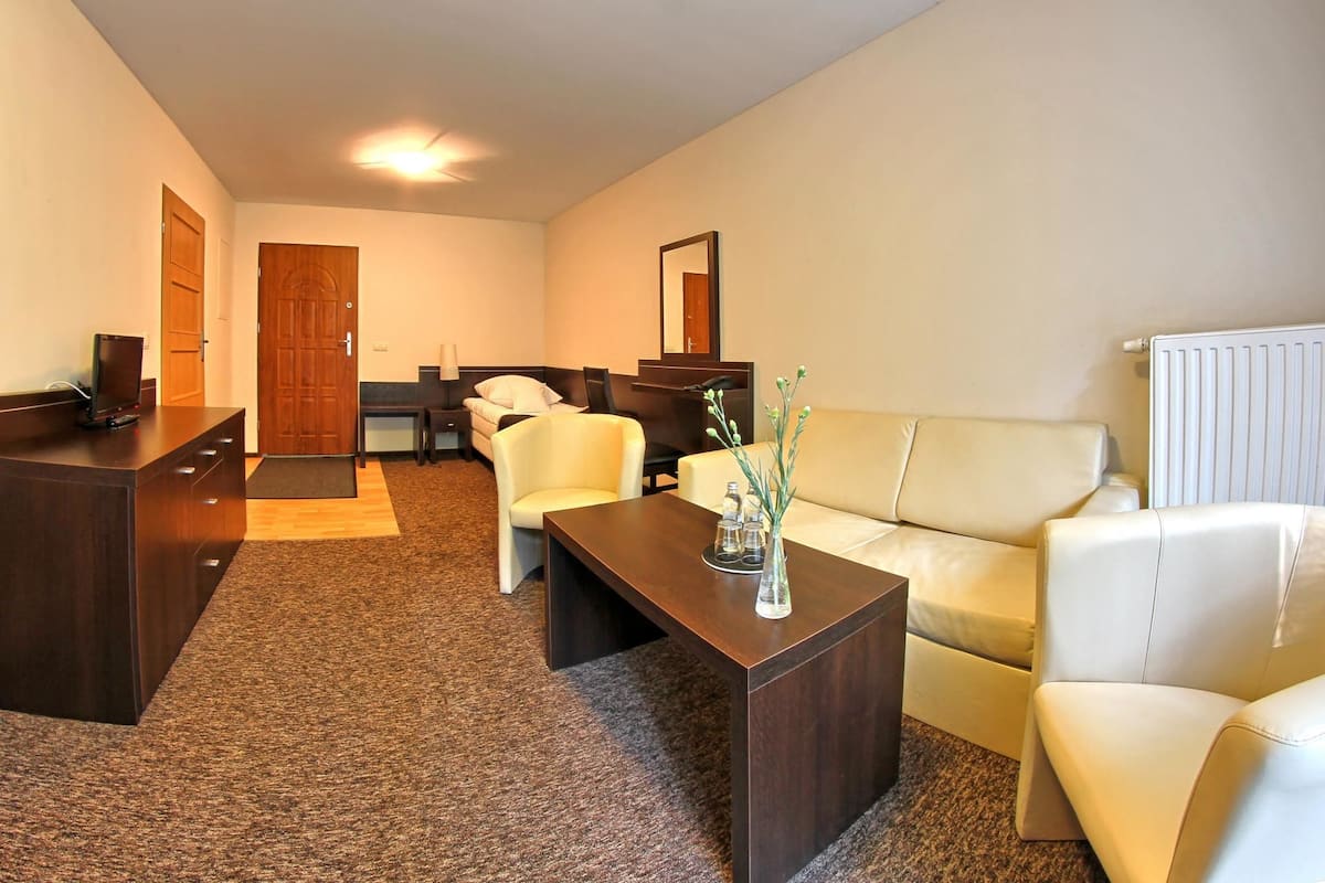 Ein Hotelzimmer mit Schreibtisch, Bett, Sofa und Couchtisch.