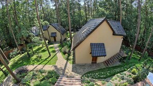 Une rangée de petits bâtiments à un seul étage, dotés de toits inclinés, entourés d’une forêt luxuriante.