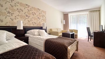 A hotel room with two beds, a sofa, a desk, and a TV.