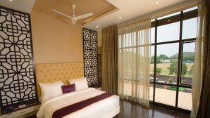 A bedroom with a large bed, a ceiling fan, and a view of a green landscape through large windows. - St Parklane Airport Hotel Chennai (Chennai)