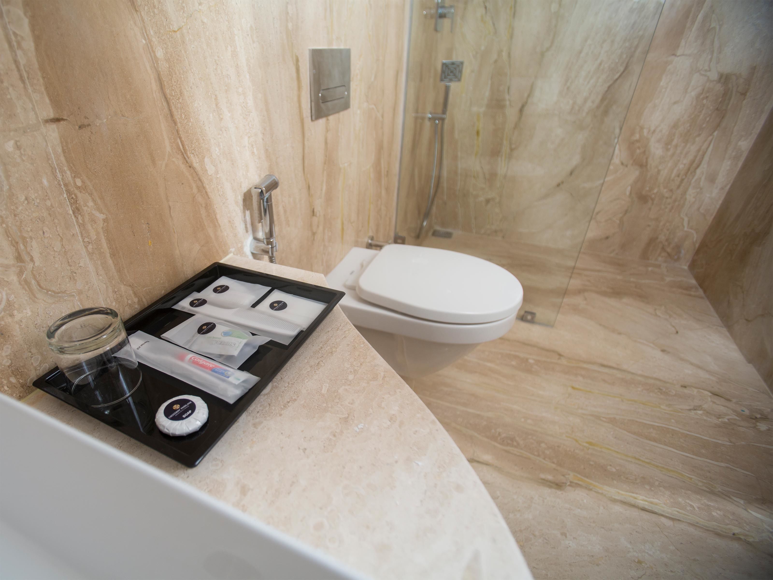 A bathroom with a marble floor, a white toilet, and a shower area.