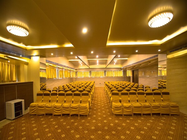 A conference room with rows of chairs, a podium, and a patterned carpet.
