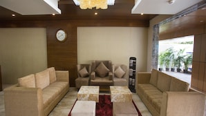 A spacious living area with a large chandelier, a clock on the wall, and a view of the outside through a glass door. - St Parklane Airport Hotel Chennai (Chennai)