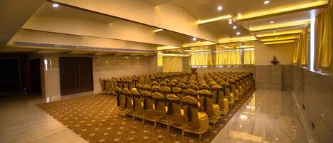 A conference room with rows of chairs, a patterned carpet, and a polished floor.