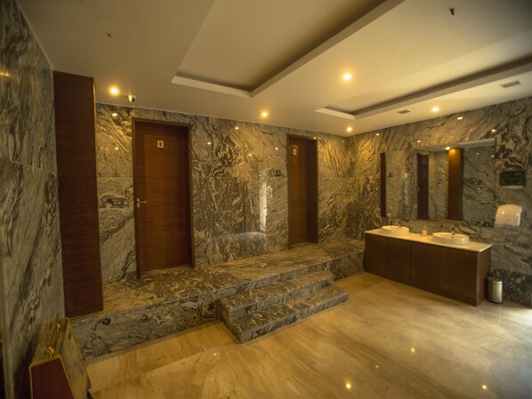 A luxurious bathroom with marble walls, a large sink, and a mirror.