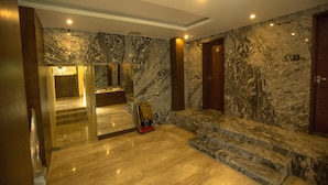 A spacious lobby with marble walls and floors, a large mirror, and a staircase leading to upper floors. - St Parklane Airport Hotel Chennai (Chennai)
