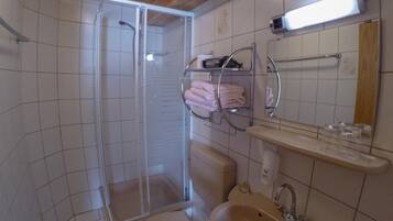 Un baño con ducha, inodoro, lavamanos y perchero para toallas.