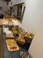 Montaje de bufé con diversos alimentos, como pan, pasteles y salsas.
