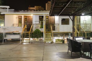 A wooden deck with outdoor furniture, a staircase, and a building with multiple doors and windows.