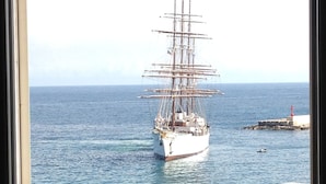 Un barco de gran tamaño atracado en un muelle, con agua azul cristalina y un mar tranquilo al fondo.