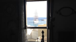 Una habitación con un amplio ventanal que da a un puerto, una cama y un radiador.