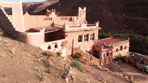 A traditional mud-brick building with a flat roof and a staircase leading to the upper levels. - Dar Zara (Ighrem N'Ougdal)