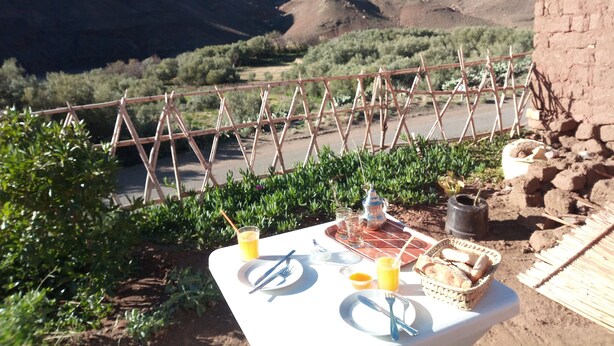 A table set outdoors with a view of a valley and mountains. - Dar Zara (Ighrem N'Ougdal)