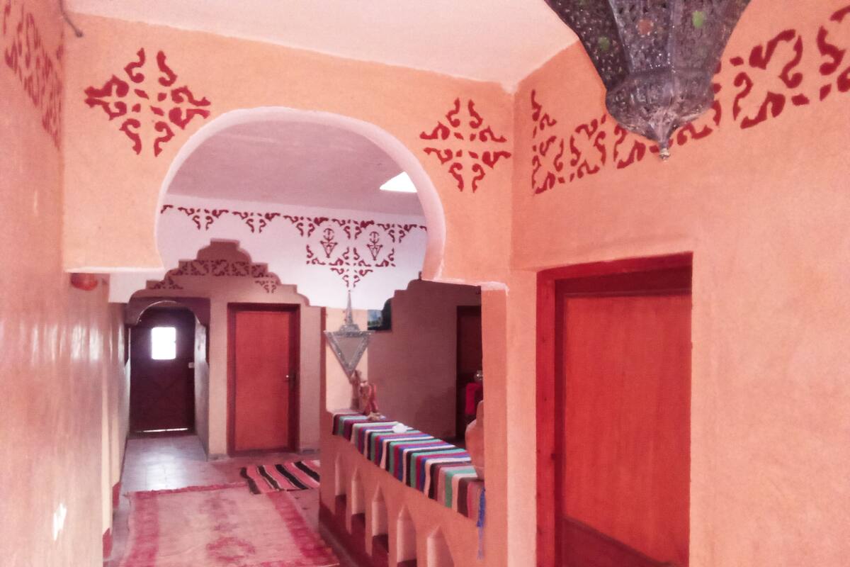A hallway with a patterned carpet, a row of chairs, and a decorative archway.