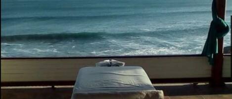 A room with a bed near a large window overlooking the ocean.