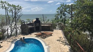 A swimming pool with a stone deck, lounge chairs, and a barbecue area overlooking the sea. - Magnific Rock - Surf Resort & Yoga Retreat Nicaragua - Hostel (Tola)