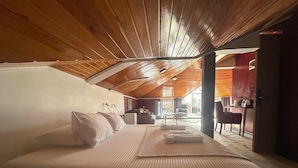 Un dormitorio con una cama grande, techo de madera y vista al comedor.
