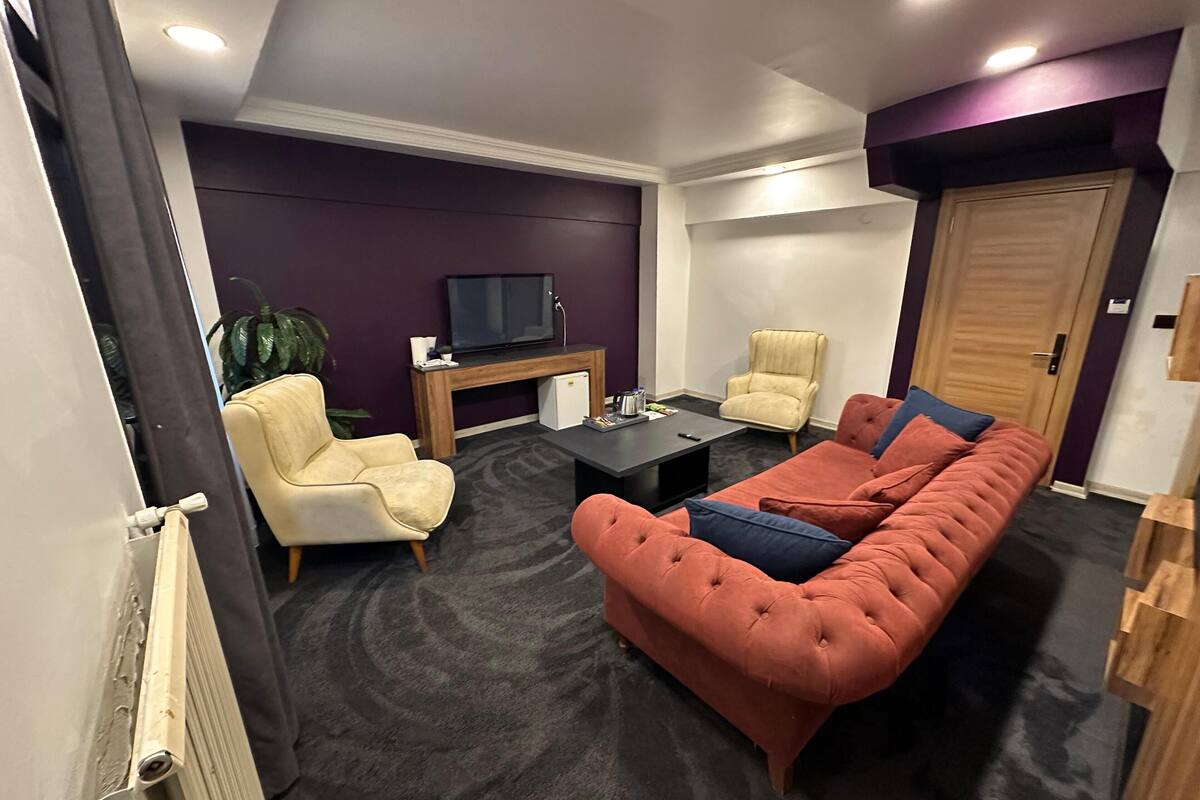 Un salon moderne comprenant un canapé, des fauteuils, une table basse, un téléviseur et un petit bureau.