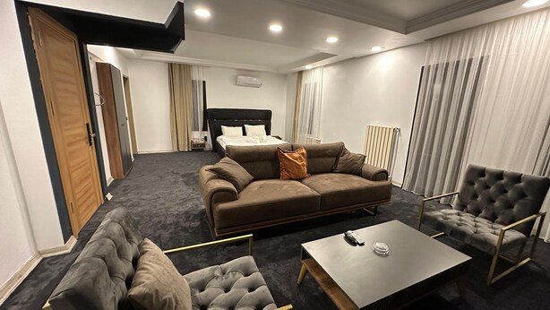 Una habitación de hotel moderna con sofá, sillón y una pequeña mesa.
