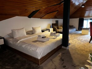 A spacious bedroom with a large bed, a wooden ceiling, and a view of a living area. - Mavilla Hotel (Beykoz)