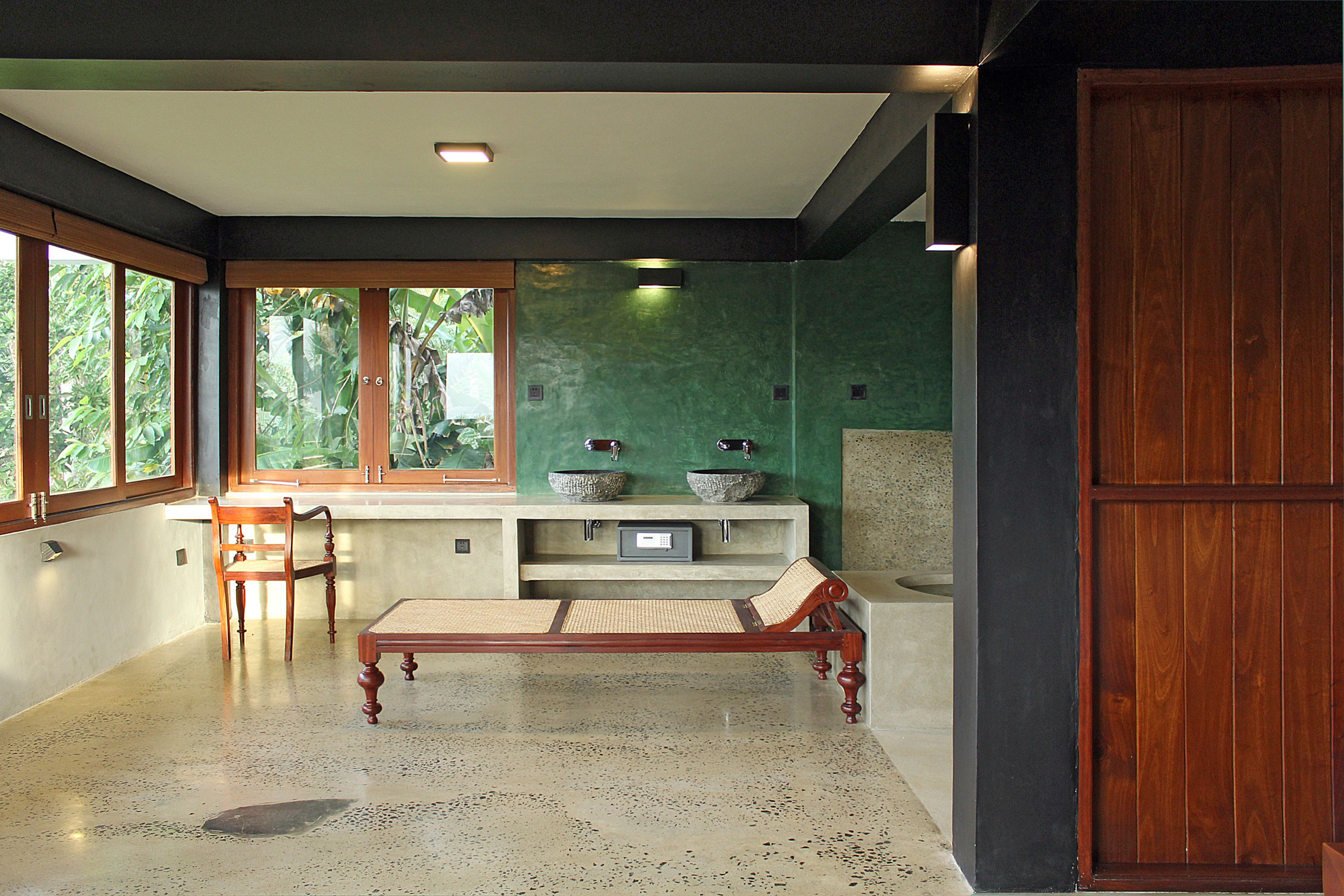 A room with a wooden bench, a small table, and a window with a view of greenery.