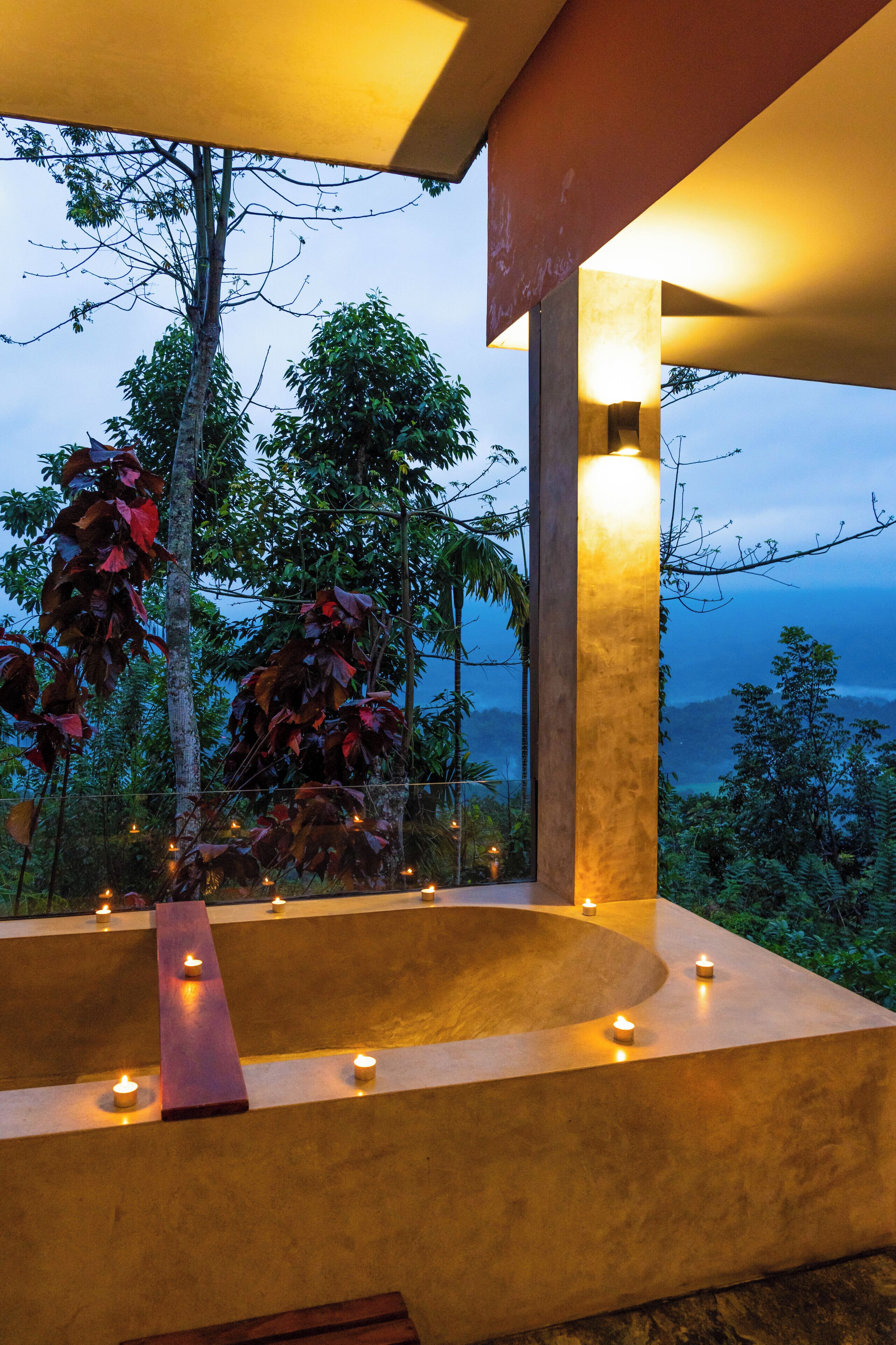 A spa area with a large bathtub, candles, and a view of the surrounding landscape.