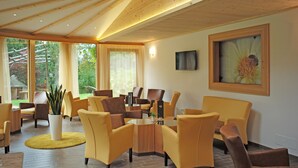 Una sala de estar moderna con sofás amarillos, una mesa de centro y un ventanal con vistas al jardín.