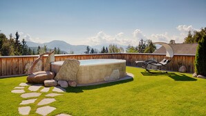 Un patio trasero con jacuzzi, silla de descanso y un sendero de piedra.