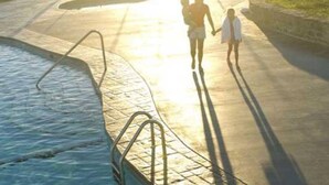 A swimming pool with a metal ladder and a concrete deck.