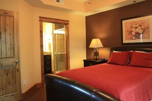 A bedroom with a bed, a nightstand, a lamp, a mirror, and a wooden door. - #721: Trout Hill Condo at Fall Creek Falls (Fall Creek Falls)